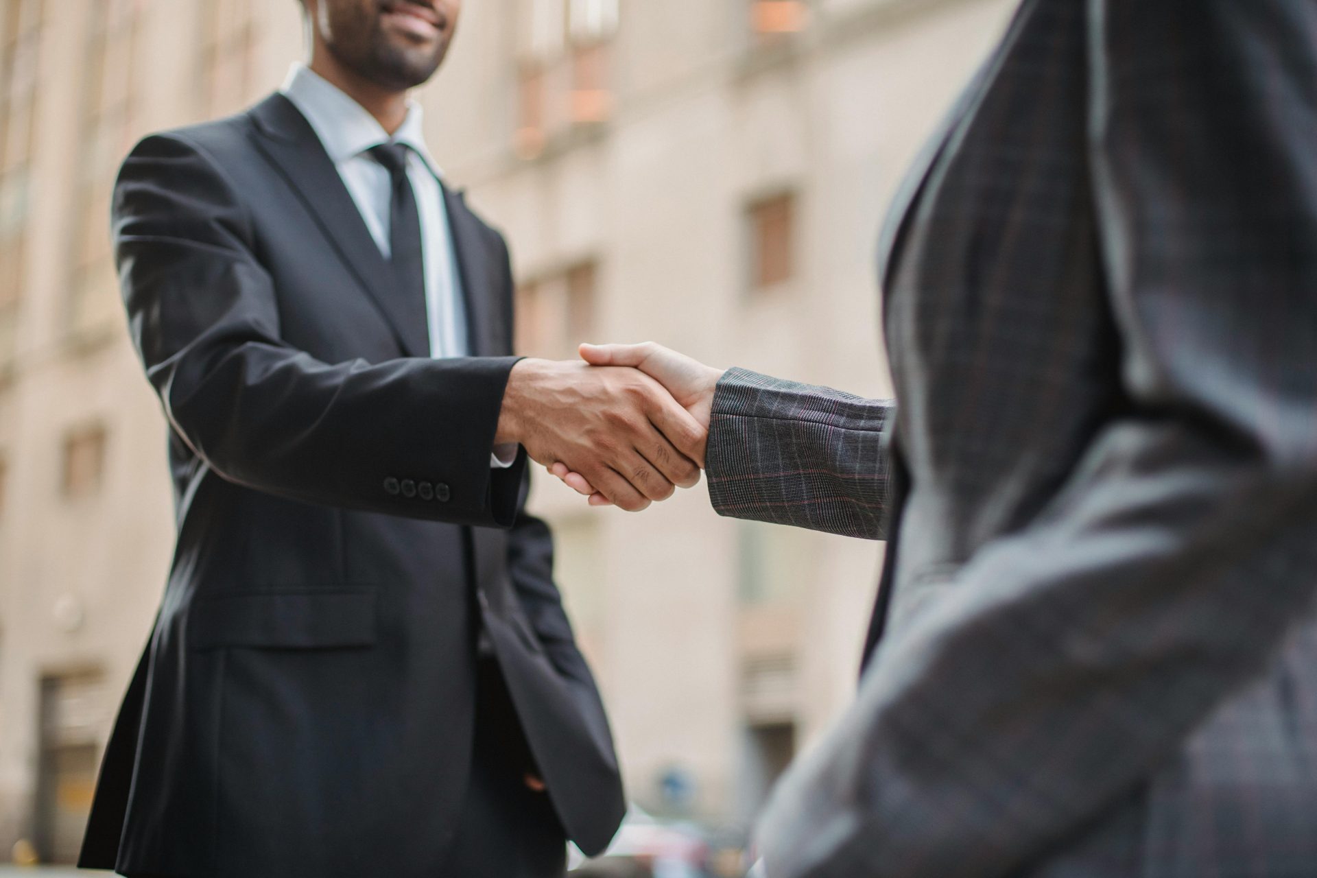 Geschäftsleute begrüßen sich im Freien mit einem Handschlag, der die Partnerschaft symbolisiert.